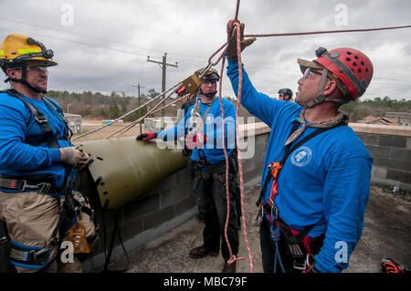 Les pompiers du Mississippi Task Force de l'équipe de recherche et sauvetage en milieu urbain à vérifier leurs noeuds et les angles à laquelle leurs cordes sont a souligné, avant de descendre sur les poulies et les faisceaux du toit d'un bâtiment effondré simulé au cours de l'exercice de formation Sud 18 PATRIOT, au camp Shelby, Mississippi, le 14 février 2018. PATRIOT Sud, une joint-agency l'exercice d'entraînement aux opérations, l'accent sur la préparation aux catastrophes naturelles pour non seulement des unités de la Garde nationale de partout au pays, mais aussi les premiers intervenants civils. (Ohio Air National Guard Banque D'Images