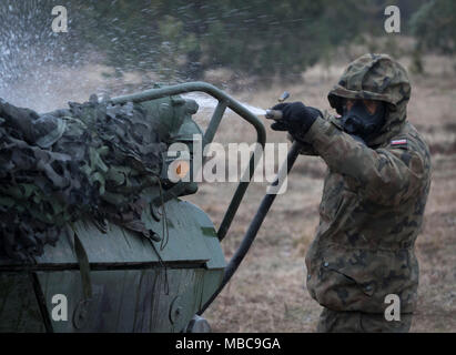 Un soldat polonais avec le 1er Bataillon, 15e Brigade mécanisée, procède à un lavage pour décontaminer un Stryker américain tout en menant à une formation de contamination près de la gamme Bemowo Piskie Domaine de formation, Pologne, 16 février 2018. Ce soldat est une partie de l'unique groupe de combat multinationales, composé de États-Unis, Royaume-Uni, croate et soldats roumains qui servent avec la 15e Brigade mécanisée polonaise comme une force de dissuasion dans le nord-est de la Pologne à l'appui de l'OTAN vers l'amélioration de la présence. (U.S. Army Banque D'Images