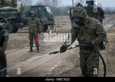 Un soldat polonais avec le 1er Bataillon, 15e Brigade mécanisée, procède à un lavage pour décontaminer un Stryker américain tout en menant à une formation de contamination près de la gamme Bemowo Piskie Domaine de formation, Pologne, 16 février 2018. Ces soldats sont une partie de l'unique groupe de combat multinationales, composé de États-Unis, Royaume-Uni, croate et soldats roumains qui servent avec la 15e Brigade mécanisée polonaise comme une force de dissuasion dans le nord-est de la Pologne à l'appui de l'OTAN vers l'amélioration de la présence. (U.S. Army Banque D'Images
