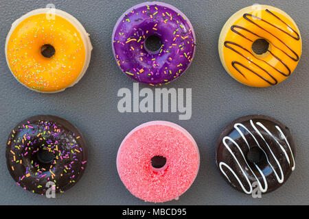 Aimants en forme de donuts sur fond gris. Différentes couleurs aimants, symbole de la malbouffe. Banque D'Images