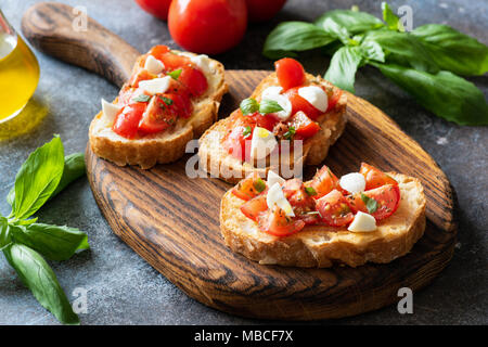 Bruschetta à la tomate cerise et de mozzarella sur la planche à découper en bois. La cuisine italienne. Ou Antipasti apéritif Banque D'Images