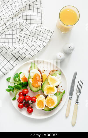 L'avocat et sain et toasts oeufs jus d'orange pour le petit-déjeuner sur fond blanc. Vue de dessus, des laïcs, des modes de vie moderne Banque D'Images