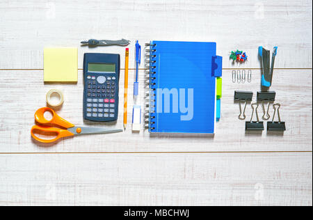 Vue d'une table en bois avec un ordinateur portable, stylo, crayon, caoutchouc, ciseaux, ruban adhésif, étriers, agrafeuse, agrafes, épingles et une calculatrice dans une belle vue Banque D'Images