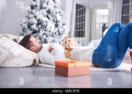 Un beau couple allongé sur le sol avec l'arbre de Noël et les cadeaux. Banque D'Images