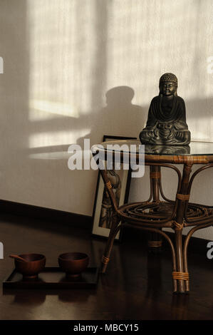 Statuette de Bouddha sur la table. Deux bols sur le plancher. Banque D'Images