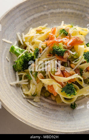 L'Italien tagliatelle avec coupes de frites filet de saumon, le brocoli, les pois et l'aneth dans la plaque en céramique Banque D'Images