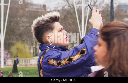 Une jeune femme distinctif de prendre une photo sur son smartphone dans le salon devant le palais de Buckingham, Londres Banque D'Images