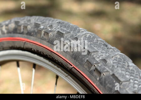 Close up sur un pneu d'un vélo de montagne avec l'arrière-plan flou vert et brun Banque D'Images