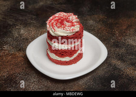 Round Red Velvet Cake avec de la crème sur la plaque blanche, fond brun Banque D'Images