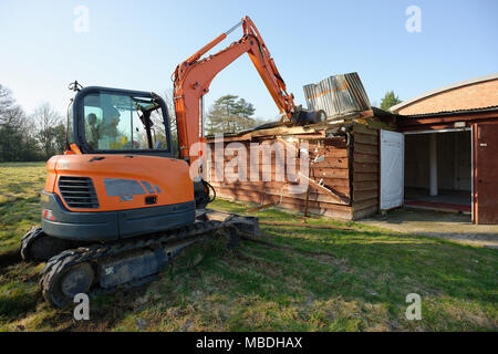 Un grand digger utilisés pour démolir une vieille grange en bois. Banque D'Images