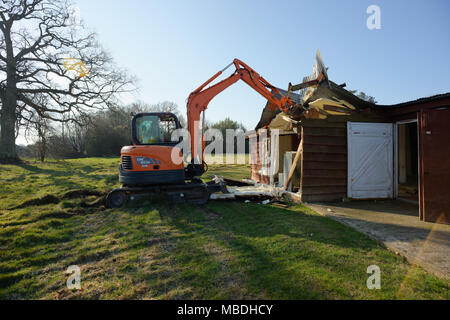 Un grand digger utilisés pour démolir une vieille grange en bois. Banque D'Images