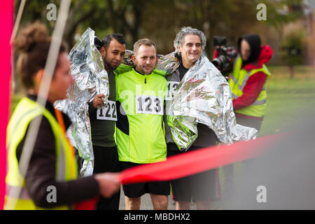 Les coureurs de marathon hommes enveloppés dans une couverture thermique à ligne d'arrivée Banque D'Images