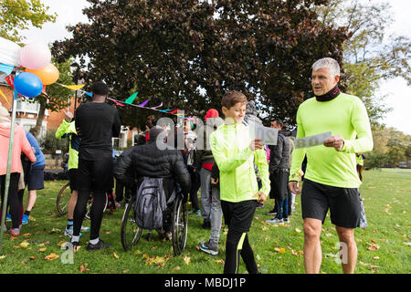 Père et fils marathon holding bavoirs de charity run dans park Banque D'Images