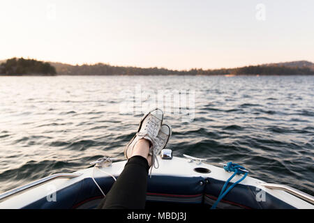 Point de vue personnel femme de plaisance avec des pieds sur le lac tranquille Banque D'Images