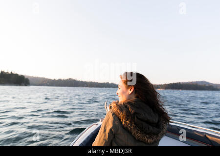 Femme souriante de bateau sur le lac tranquille, ensoleillée Banque D'Images