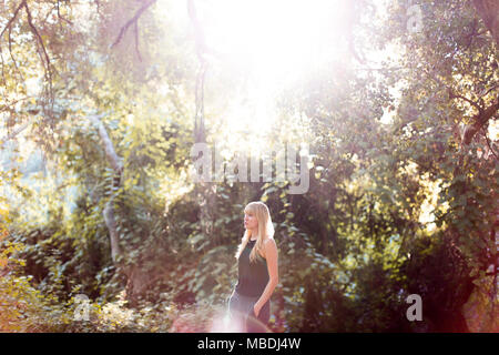 Serene woman standing in sunny summer woods Banque D'Images