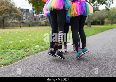 Dames enthousiastes en tutus sautant sur sentier du parc Banque D'Images