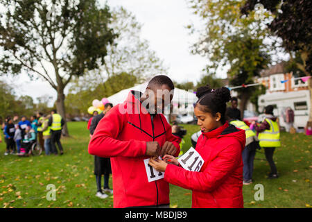 L'épinglage fille bib marathon sur père runner de charity run dans park Banque D'Images