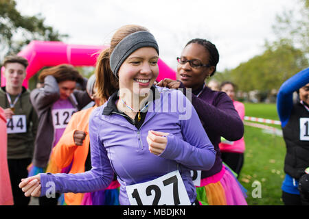Woman pinning bib marathon sur ami de charity run dans park Banque D'Images