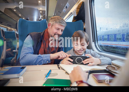 Père et fils à l'aide de smart phone sur le train de passagers Banque D'Images