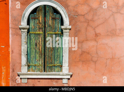 À la recherche jusqu'à un vieux châssis de fenêtre en stuc baigné de lumière, avec blanc des cadres de fenêtre, à Venise, Italie. Banque D'Images