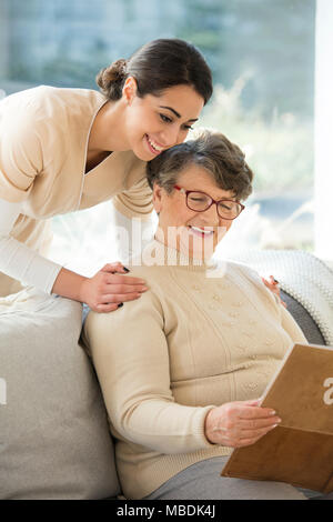 Belle infirmière et heureuse grand-mère à la ensemble à un album photo dans un haut Accueil Banque D'Images