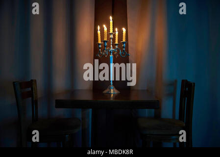 Brûler des bougies dans les chandeliers debout sur une table vide avec deux chaises dans le crépuscule. Copy space Banque D'Images