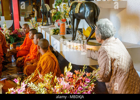 Une vieille femme s'allume d'encens alors que les moines bouddhistes assis sur le sol de réciter des mantras pour le Nouvel An khmer à la Grande Pagode de Vincennes. Banque D'Images