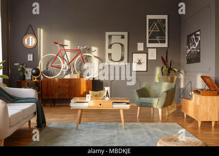 Table basse en bois avec papiers, sur un vélo rouge et vert du cabinet dans un fauteuil d'intérieur salon rétro Banque D'Images