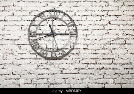 Close up old vintage style retro horloge murale en métal sur fond de mur de briques peintes en blanc grunge Banque D'Images