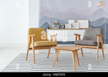 Fauteuil gris et jaune à côté d'une table de bois sur tapis à rayures à l'intérieur confortable salle de séjour Banque D'Images