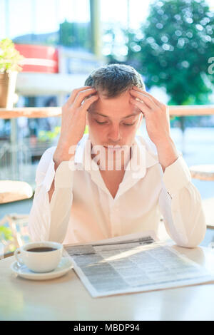 L'homme réfléchi de lire le journal dans un café de la rue à l'heure du déjeuner. Concept de gens d'affaires. Banque D'Images