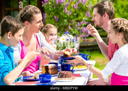 Le café de la famille en temps de manger un gâteau jardin Banque D'Images