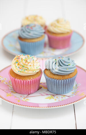 Cupcakes vanille colorés sur une plaque avec une tasse de thé Banque D'Images
