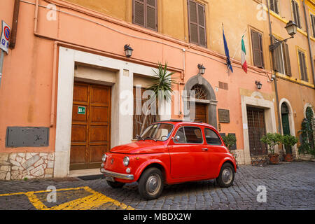 Voir l'emblématique d'une vieille Fiat 500 rouge garée dans une rue pavée à Rome, en Italie, à l'extérieur d'un bâtiment sous pavillon italien. Les plaques d'afficher une MI Banque D'Images