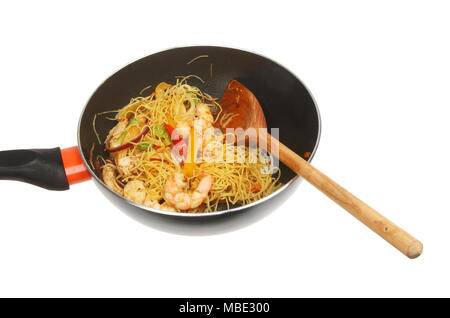 Crevettes nouilles de Singapour et faire sauter les légumes dans un wok avec une cuillère en bois isolés contre white Banque D'Images