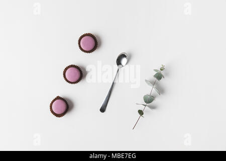 Mise à plat avec ses macarons, cuillère et eucalyptus sur surface blanche Banque D'Images