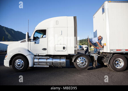 Homme noir conducteur du camion les câbles d'alimentation de remorque pour camion-tracteur à un arrêt de camion. Banque D'Images