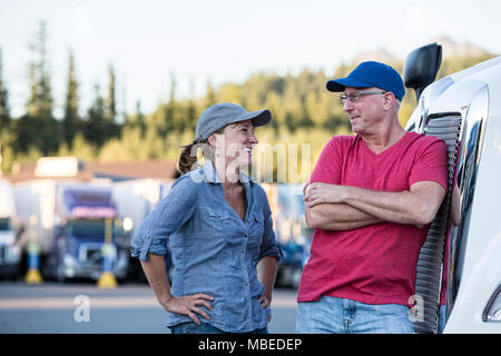 L'homme et de la femme de race blanche de l'équipe de conduite de parler en face d'un grand camion à un arrêt de camion. Banque D'Images