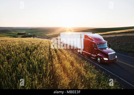 Bien que la conduite de camions commerciaux de champs de blé l'Est de Washington, USA au coucher du soleil. Banque D'Images