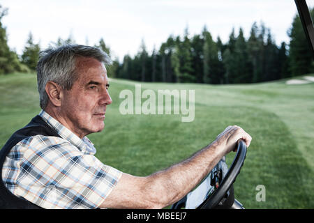 Golfeur aîné la conduite d'un chariot de golf sur le chemin d'un chariot de golf. Banque D'Images