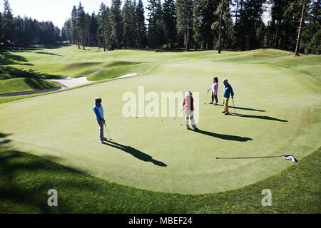 Vue de dessus de quatre golfeurs jouer au golf sur un green dans la distance. Banque D'Images
