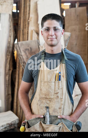 Vue d'un jeune homme de race blanche employée d'usine portant un tablier dans une usine à bois. Banque D'Images