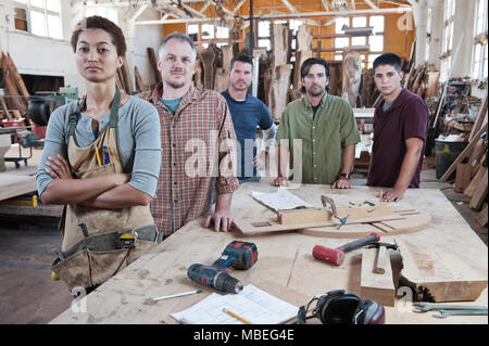 Équipe de travailleurs de l'usine multi-raciale debout près d'un poste de travail dans une grande usine de travail du bois. Banque D'Images