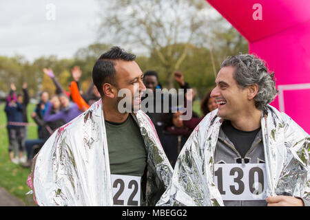 Male marathoniens enveloppés dans des couvertures thermiques à ligne d'arrivée Banque D'Images