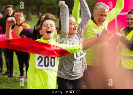 Garçon enthousiaste runner crossing charité exécuter ligne d'arrivée avec la famille Banque D'Images