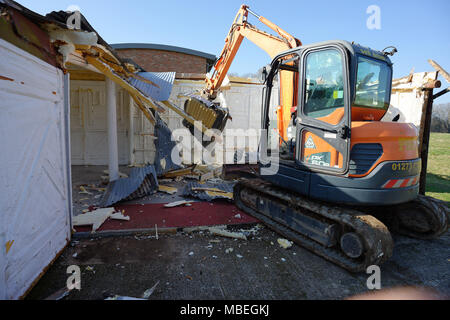 Un grand digger utilisés pour démolir une vieille grange en bois. Banque D'Images