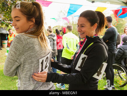 L'épinglage mère bib marathon sur fille de charity run dans park Banque D'Images
