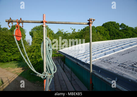 Poulie et corde avec toit en zinc du bâtiment derrière. Le ruissellement des eaux de pluie en structure convexe gouttières zinc. Banque D'Images