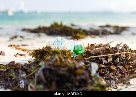Bouteille en plastique se trouve des déchets rejetés sur le rivage d'une plage de sable blanc Banque D'Images